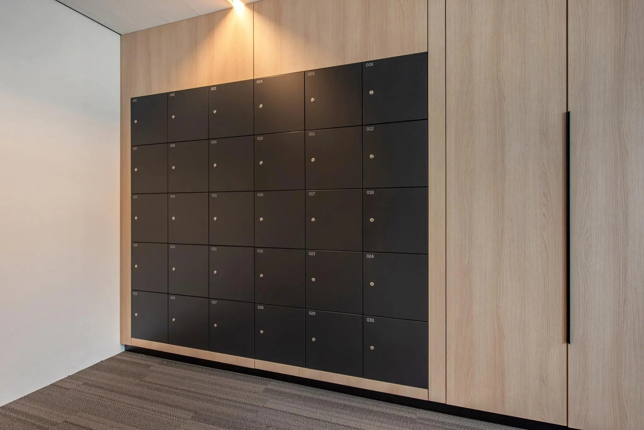 Zwarte lockerkast met dertig genummerde vakken in een moderne, houten wand in de Grote Marktstraat.